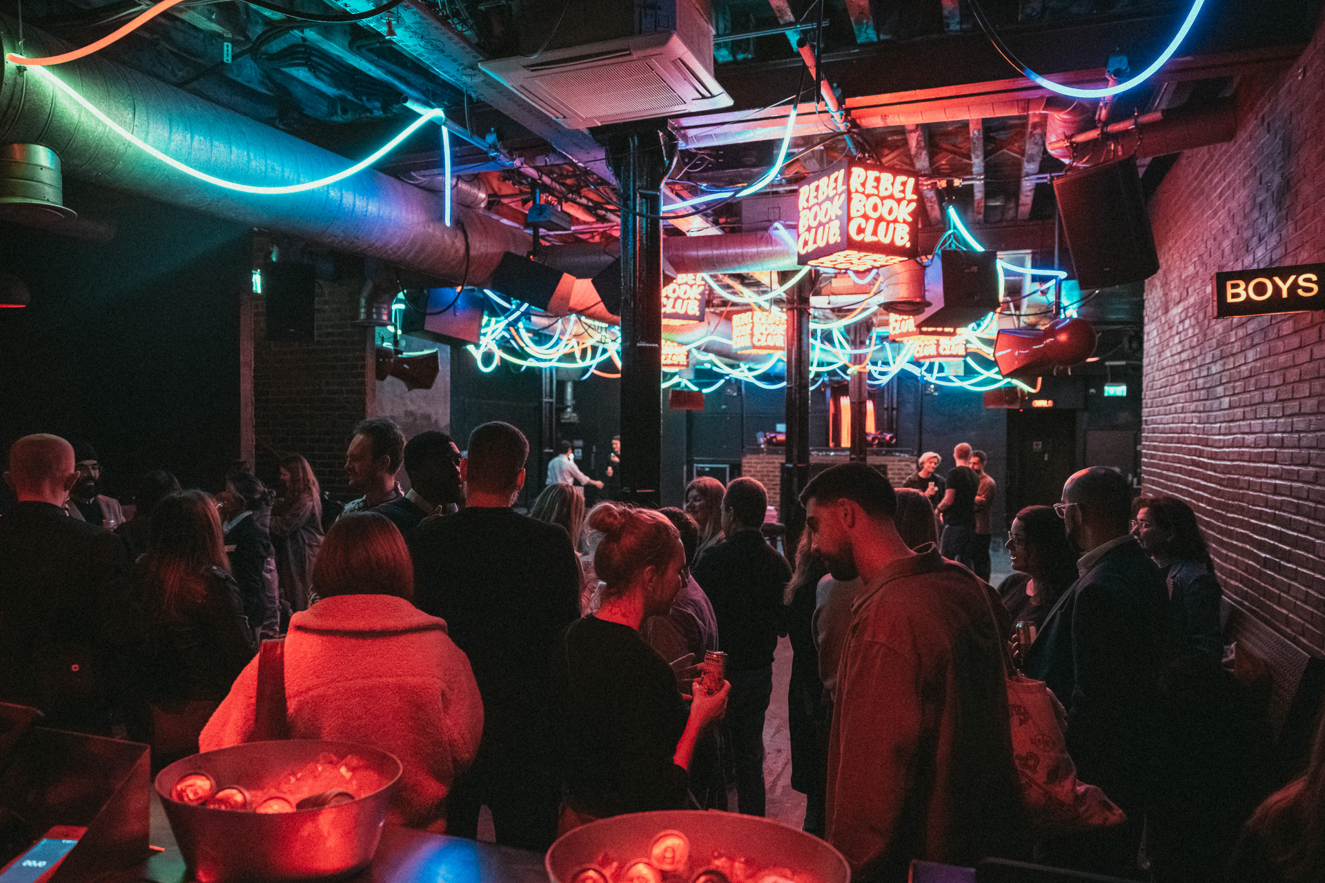 Rebel Book Club neon signs above the crowd