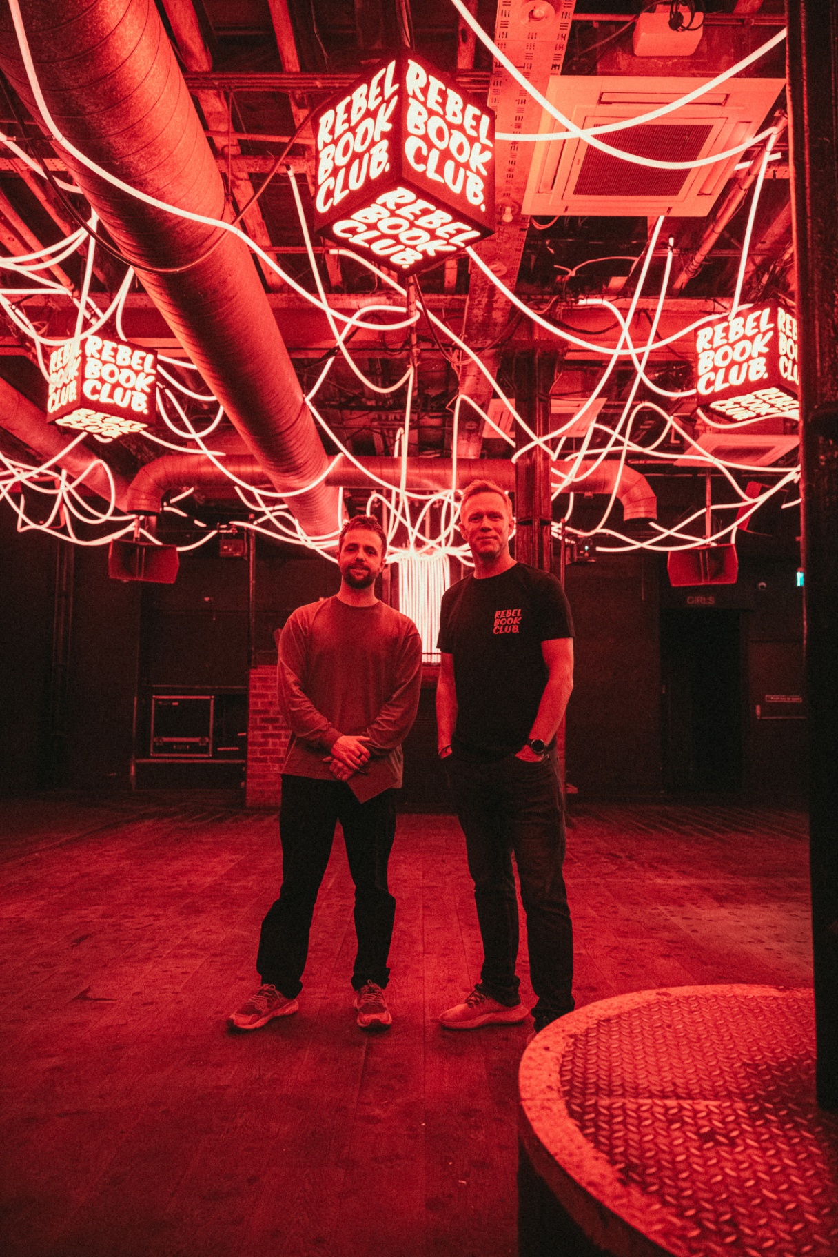 Founders under the Rebel Book Club neon installation